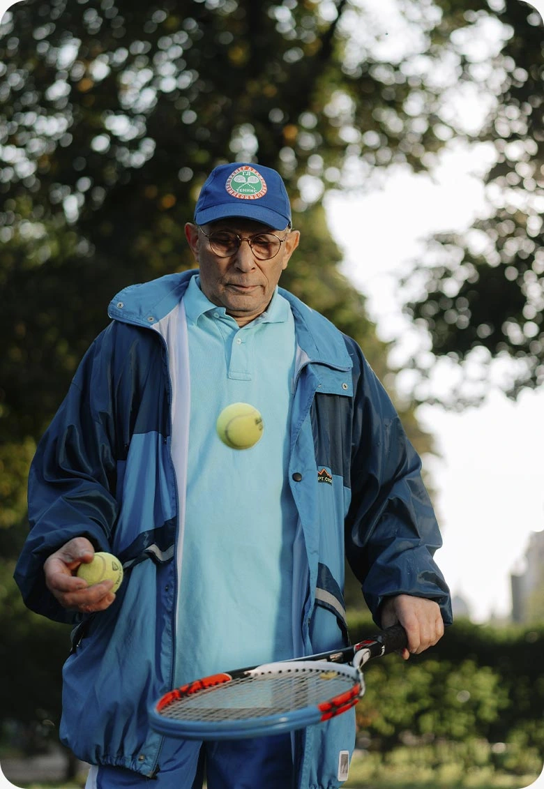 Active Senior Man Playing Tennis Outdoors | Comfort Home Care Active senior man practicing tennis in a park