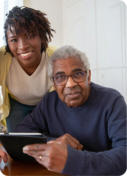Home Caregiver Helping a Senior Use Technology | Comfort Home Care Home caregiver helping a senior man use a tablet