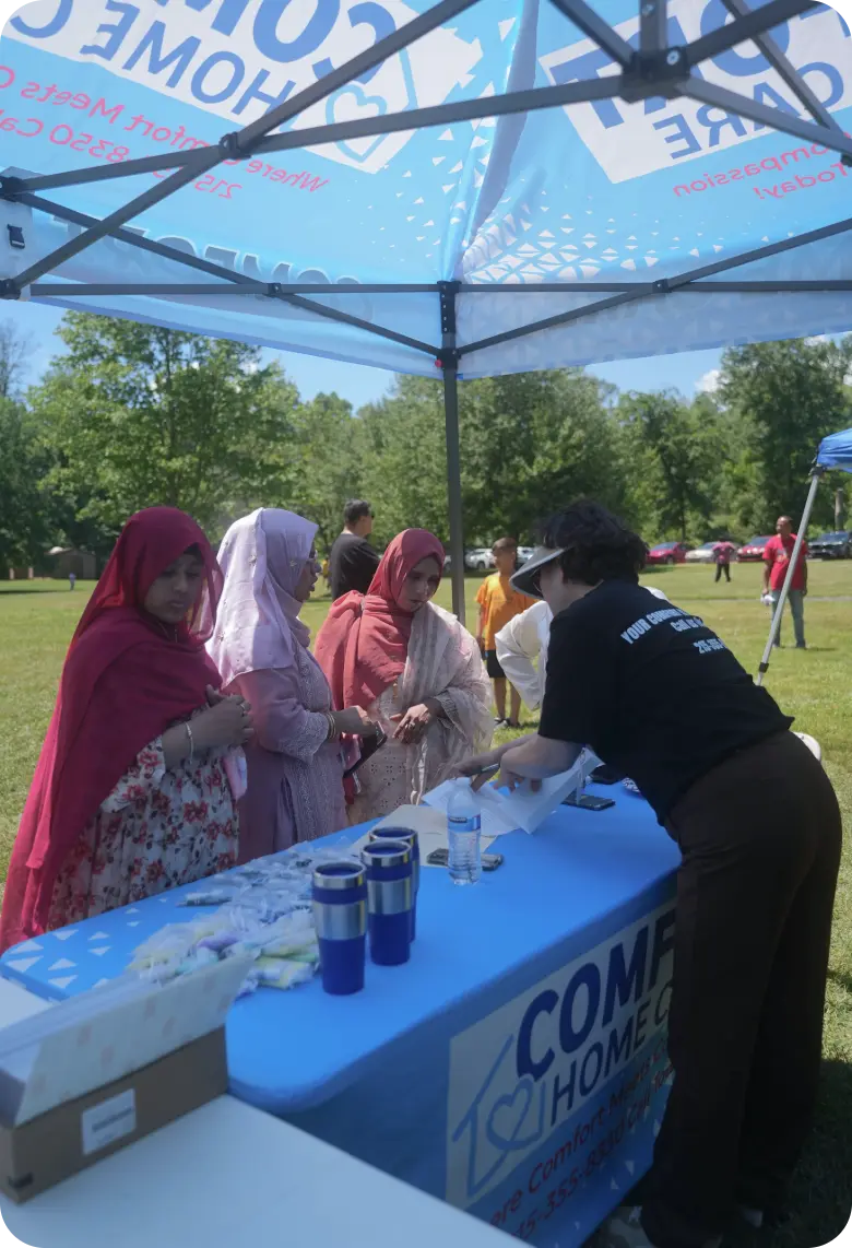 Comfort Home Care team member assisting visitors at a community outreach event booth