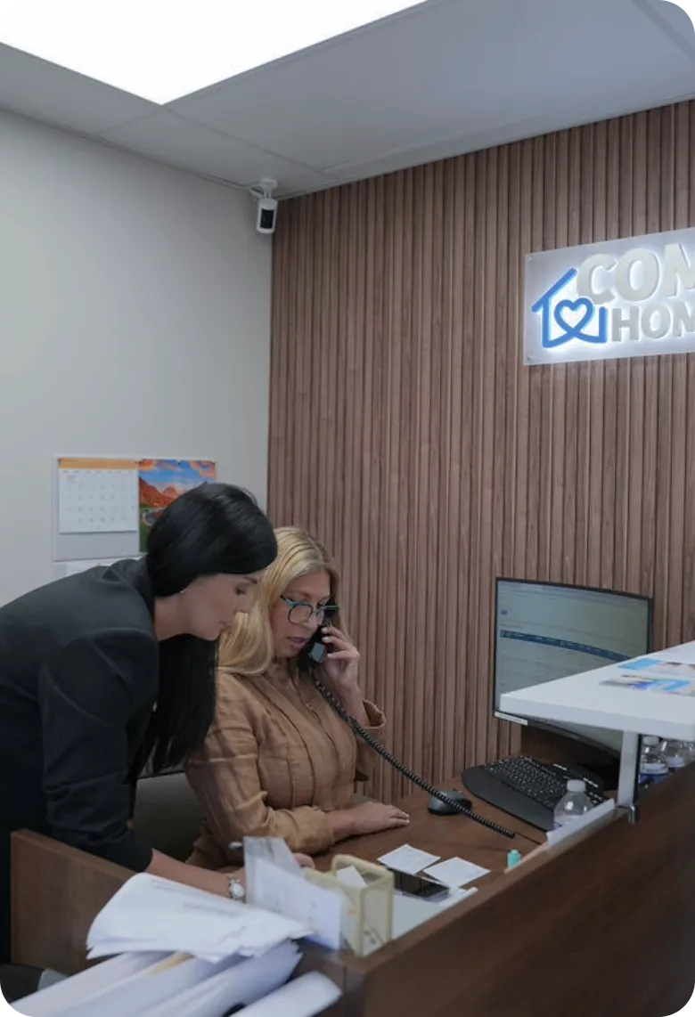 Comfort Home Care Office Staff Providing Phone Support | Comfort Home Care Two Comfort Home Care staff members assisting with a phone call in the company office