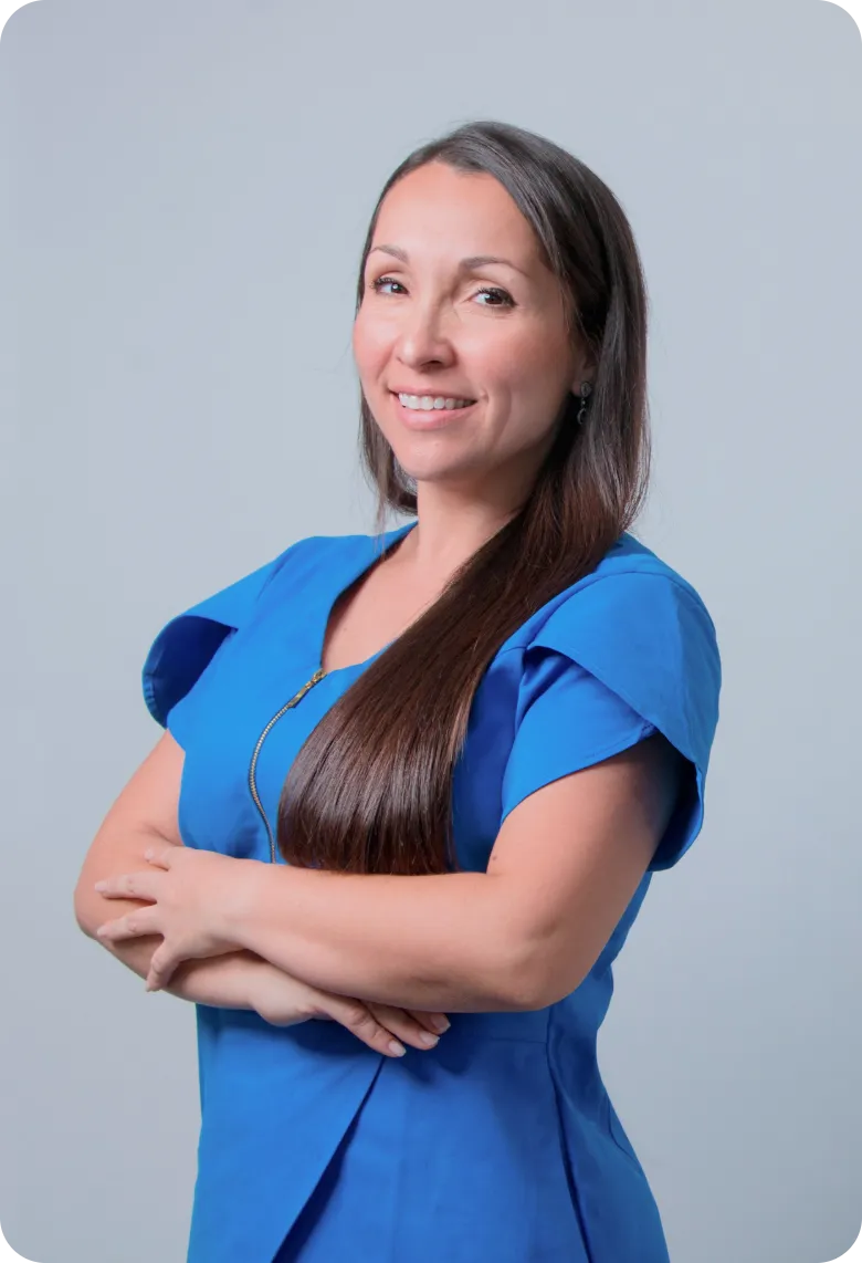 Smiling professional home caregiver in blue scrubs with arms crossed