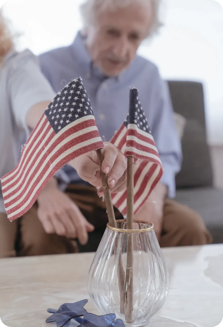 Senior couple arranging American flags in a vase at home